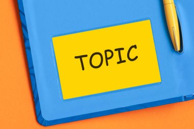 Topic kelimesi sarı not kağıdına siyah harflerle yazılmıştır. Mavi günlüğün arka planında sarı bir kalem gömülü..