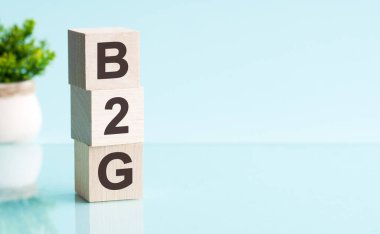 Motive edici kelimeler: 3D tahta alfabe harfli B2G parlak mavi arkaplan üzerinde kopyalanmış alan, iş konsepti. B2G - İşletmeden Hükümete