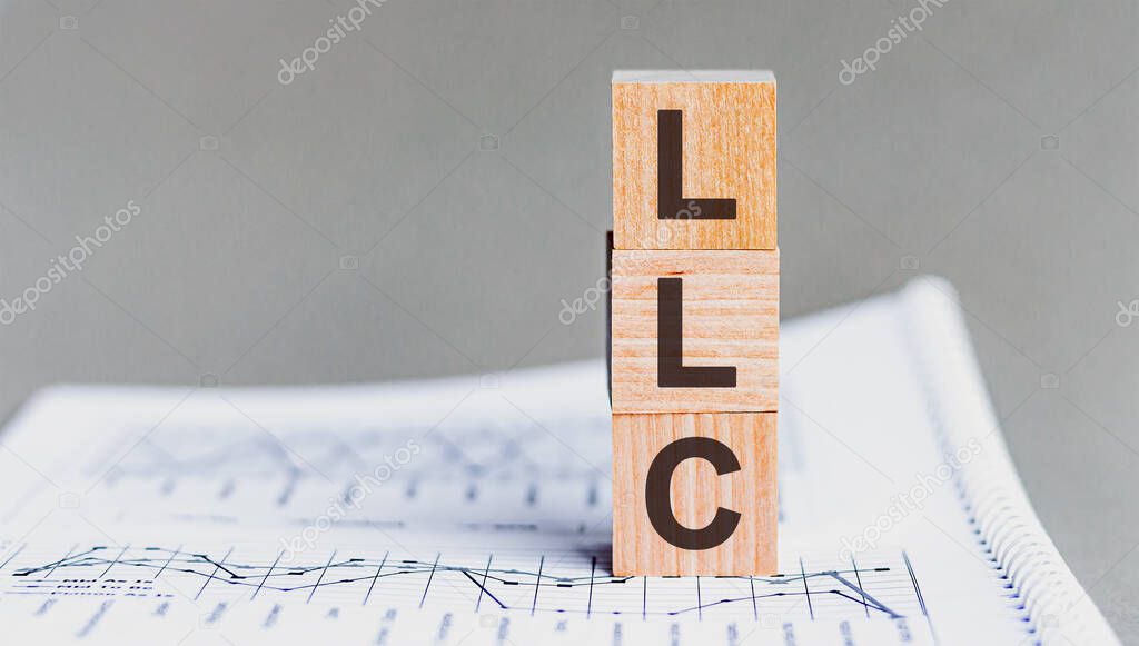 LLC - Limited liability company - acronym on wooden cubes on columns of numbers background. LLC, acronym on wooden cubes. Background - document with numbers, business concept.