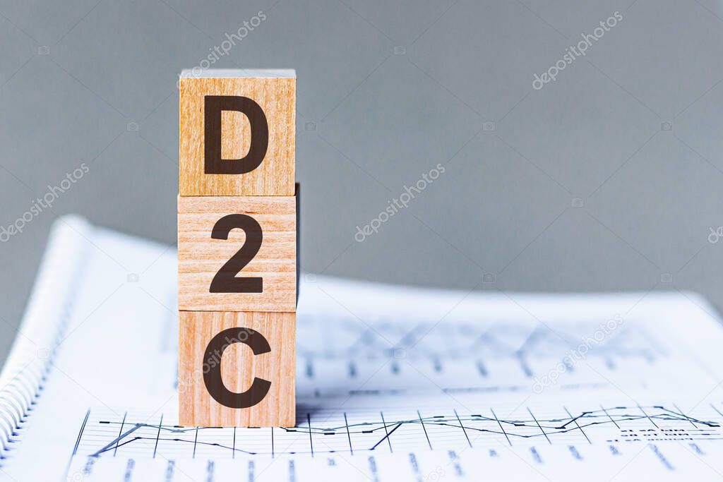 D2C - DTC Advertising Direct-to-Consumer - acronym on wooden cubes on columns of numbers background. D2C, acronym on wooden cubes. Background - document with numbers, business concept.