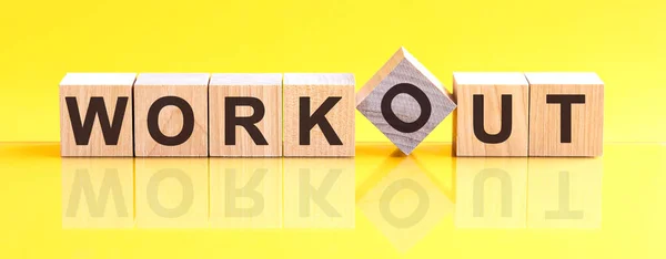 木のブロックに書かれたワークアウトの単語 ワークアウトの単語は 黄色のテーブルの上に横たわる木製の建物のブロックで作られています ビジネスコンセプト黄色の背景 — ストック写真