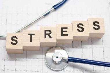 Stres kelimesi tahta bloklara, steteskop da arka planda yazılıydı. Hastane, klinik ve tıbbi otobüsler için sağlık hizmetleri kavramı.