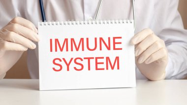 Tıp doktorunun elinde IMMUNE Sistemler Kartı. Doktorun elleri eldivenli kağıtta IMMUNE SİSTEM yazılı, tıbbi konsept..