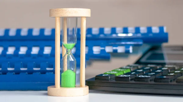 Calculadora y reloj de arena primer plano soporte en una mesa de madera blanca, concepto de negocio — Foto de Stock