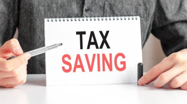 Finansal tablosunda kalem olan beyaz kartta Vergi Tasarruf metni. İş ve mali konsept