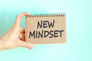 Bir iş kadınının elindeki kâğıt kâğıdına yazılmış yeni bir zihniyet yazısı. Beyaz kağıtta siyah harfler.