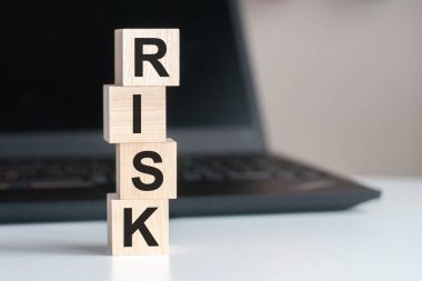 Tahta blokta, bilgisayarın klavyesinde siyah arka planda yazılan risk metni. Hizmet desteği veya assitance kavramı.