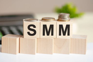 Hesap makinesi ve kelime SMM ile dolar banknotu. Banknotlar ve harfli tahta küpler. Tahta bloklar ve hesap makinesiyle kavram. SMM - Sosyal Medya Pazarlaması.