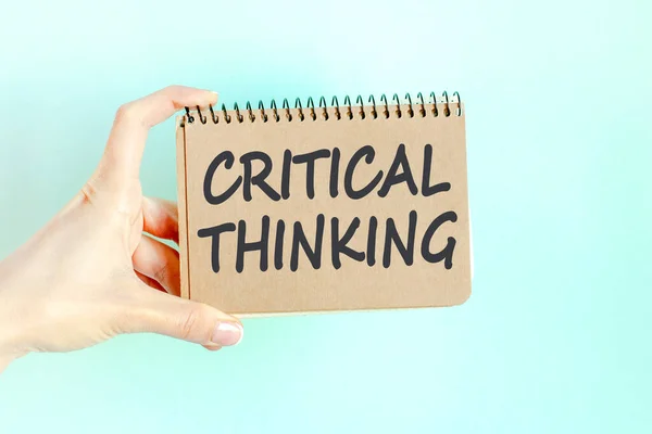 CRITICAL THINKING word inscription on card paper sheet in hands of a businesswoman. Black letters on craft colour paper. Business concept