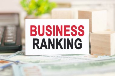 İşletme sıralaması, tahta küplerin yakınındaki beyaz kağıt kartlara, hesap makinesine ve banknotlara yazılır. İş ve Finans kavramı