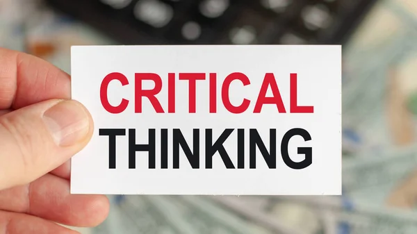 Motivational words: CRITICAL THINKING. Man holds a piece of paper with the text: CRITICAL THINKING. Business and finance concept