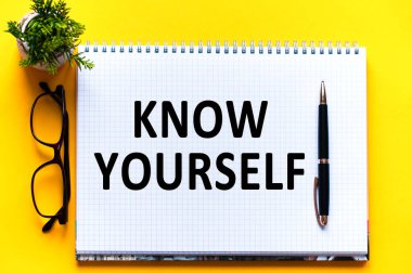 Kelime metni kendini beyaz kağıtta, siyah harflerde tanır. Sarı arka planda kalem, bardak ve yeşil çiçek. İş konsepti. Eğitim kavramı.