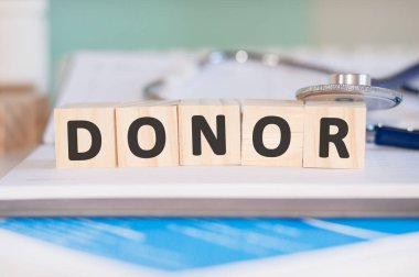 Donör kelimesi, kağıt bir arka planda steteskopun yanındaki tahta küplere yazılır. Tıbbi konsept.