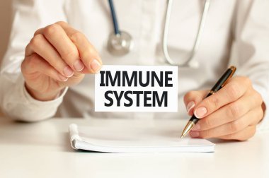 IMMUNE SYSTEM card in hands of medical Doctor. Doctor's hands a sheet of paper with text IMMUNE SYSTEM, medical concept.