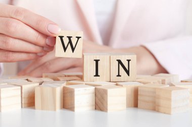 Kadın eli ve pembe arka planı olan tahta bir oyuncak bloğunda kazanmak. İş konsepti.