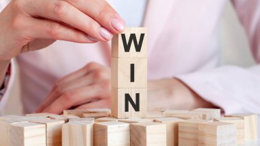 Kadın eli ve pembe arka planı olan tahta bir oyuncak bloğunda kazanmak. İş konsepti.