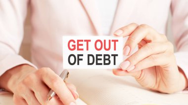 Kadın defterine gümüş bir kalem ve el ele tutuşma kartıyla şöyle yazmış: Borçtan kurtul. Pembe arka plan, ön manzara. İş ve eğitim kavramı.