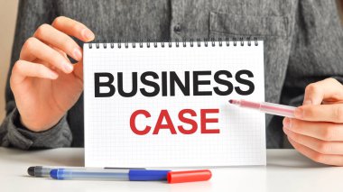 Masanın üzerinde kırmızı bir işaret ve beyaz bir kağıt tablet var. Metnin yazıldığı - BUSINESS CASE, kırmızı ve siyah harfler. İş konsepti.