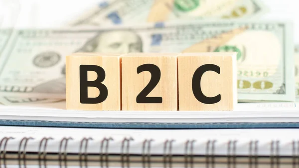 B2C. B2C short for Business-to-consumer. Business concept on wooden cubes and dollars background