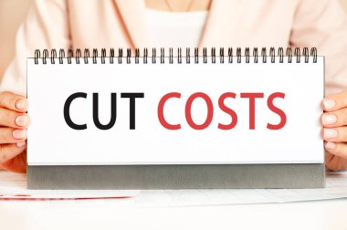 Bir karton üzerinde metin kesme maliyetleri gösteren bir işadamı