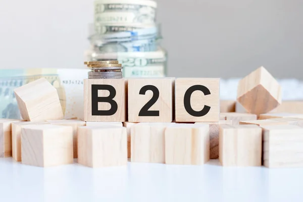 the word B2C on the wooden blocks and a bank with money in the background, business concept, B2C short for Business-to-consumer