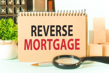 Metin rengi not defteri ve ters ipotekli. Hesap makinesi, tahta bloklar, büyüteç ve yeşil çiçekli not defteri. Not defteri kağıdındaki iş konsepti. Seçici odak.