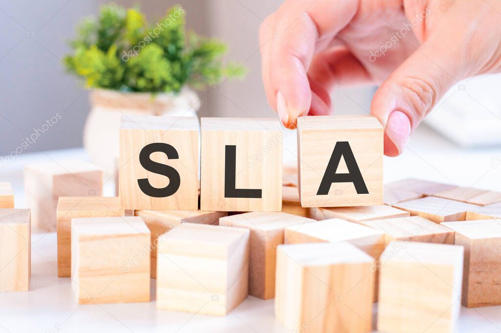 Businesswoman hand holding SLA word with wooden cube block. SLA short for Service Level Agreement. Business concepts