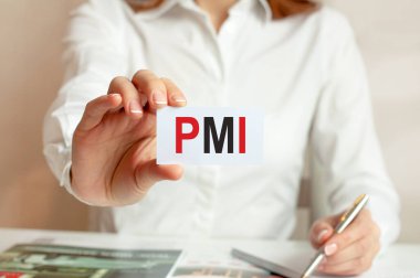 Beyaz gömlekli bir kadın üzerinde PMI yazan bir kağıt parçası tutuyor. Şirketler için iş kavramı. PMI - proje yönetimi enstitüsünün kısaltması.