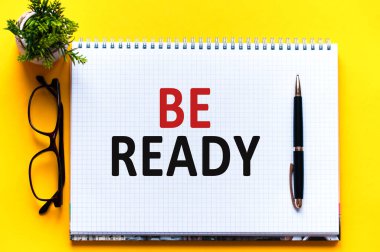 Sözcükler beyaz kağıtta, siyah harflerde hazır olsun. Sarı arka planda kalem, bardak ve yeşil çiçek. İş konsepti. Eğitim kavramı.