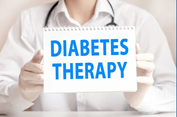 Doctor holding a white card in hands and pointing on the words DIABETES THERAPY. Healthcare conceptual for hospital, clinic and medical busines.