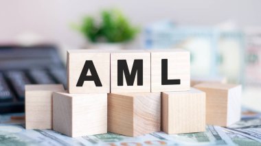 Ahşap küplere AML kelimesi, banknotlar ve arka planda hesap makinesi. AML, kara para aklamanın kısaltması. İş ve finans kavramı.