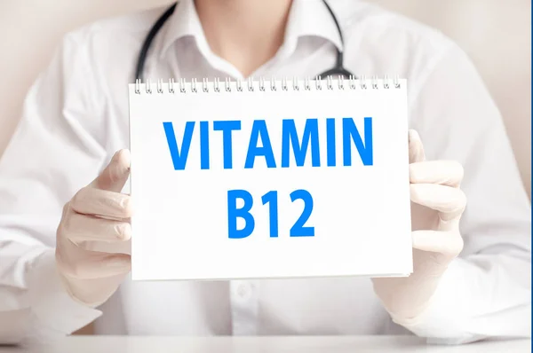 Doctor holding a white card in hands and pointing on the words vitamin b12. Healthcare conceptual for hospital, clinic and medical busines.