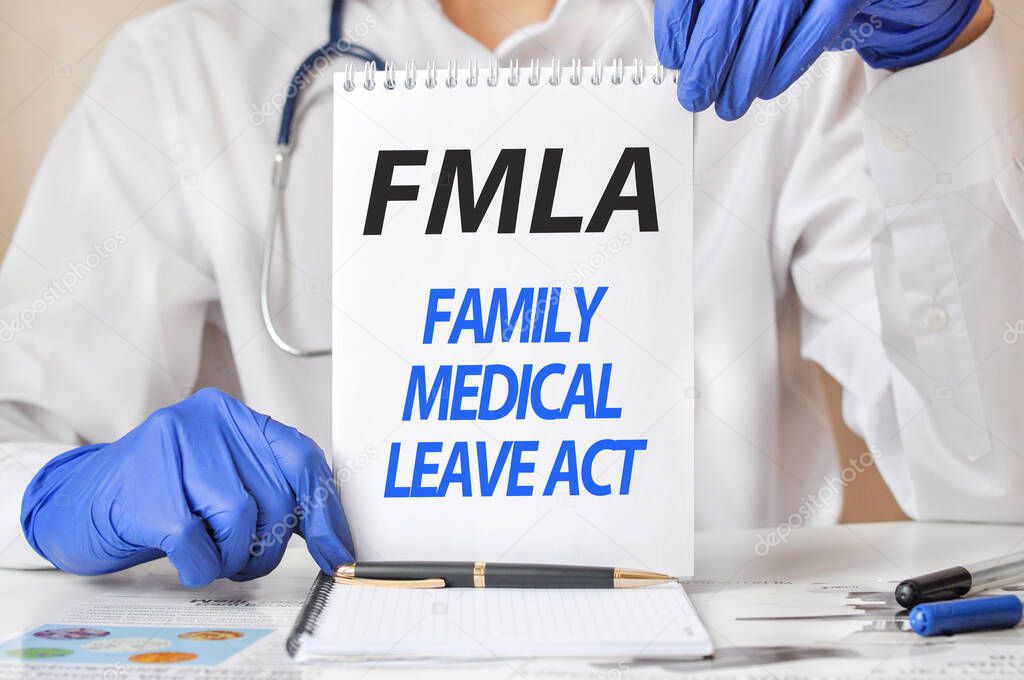 Doctor's hands in blue gloves holding a sheet of paper with text flma. fmla - short for family medical leave act, medical concept