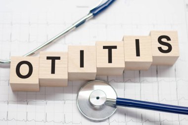 Tahta blok, doktorun masasında steteskopla OTITIS kelimesini oluşturuyor. Tıbbi konsept. Hastane, klinik ve tıp sektörü için sağlık hizmetleri kavramı.