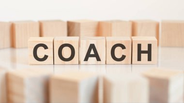 COACH kelimesi tahta küpler yapısına yazılmıştır. Parlak bir arkaplanda engeller. İş, eğitim, finansal konsept için kullanılabilir. Seçici odak.