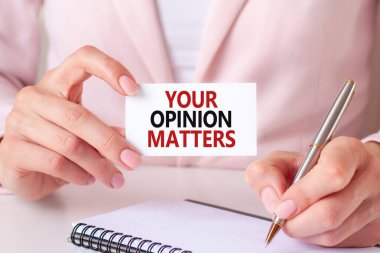 Kadın defterine gümüş bir kalem ve el sıkışma kartıyla şöyle yazmış: Senin fikrin önemli. Pembe arka plan, ön manzara. İş, eğitim, tıbbi konsept için kullanılabilir.