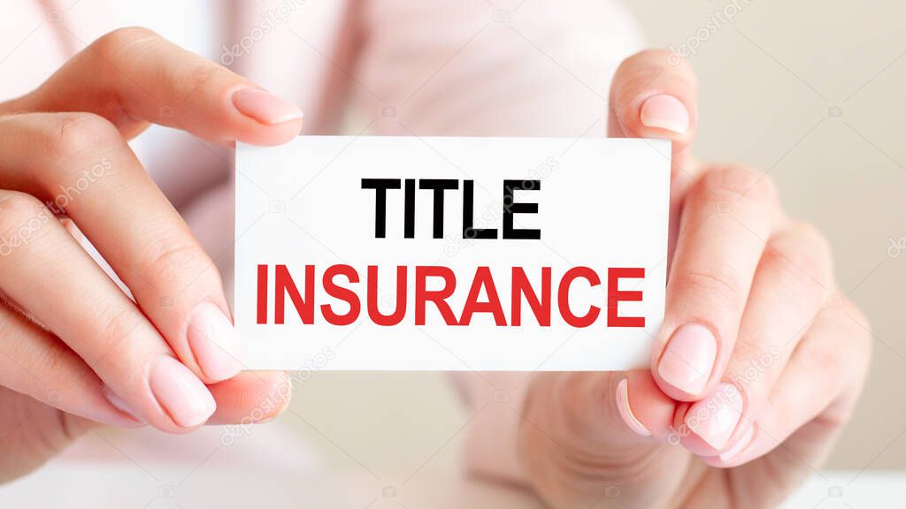 title insurance is written on a white business card in a woman's hands. Pink background. Can be used for business, advertising, education, financial