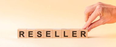 El, Reseller kelimesinin R harfinin olduğu tahta bir küp koyuyor. Kelime, masanın sarı yüzeyinde duran tahta küplere yazılmıştır. İş ve eğitim kavramları için kullanılabilir.