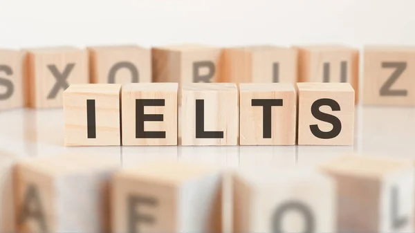 Toy wood blocks with letters IELTS on a table with light background, selective focus. IELTS - short for International English Language Testing System.