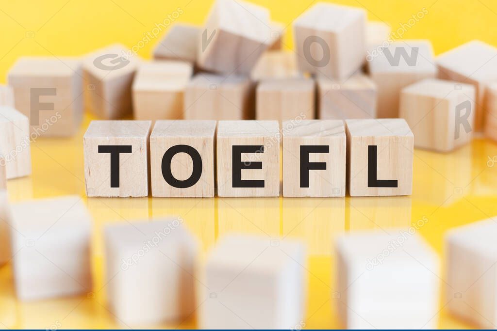 the word toefl is written on a wooden cubes structure. Blocks on a bright background. financial concept. selective focus. toeic short for Test of English as a Foreign Language