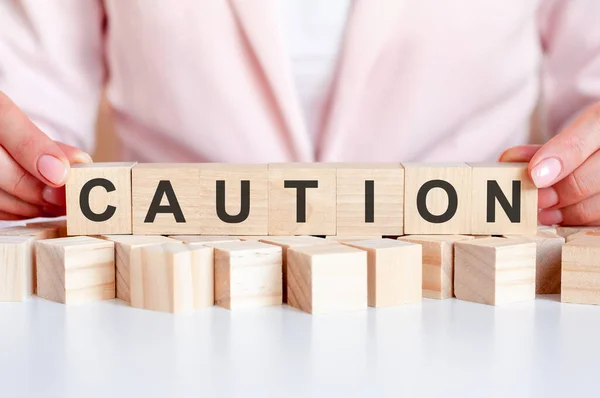 Word Caution Written Wooden Cubes Standing White Surface Table Pink — Stock Photo, Image