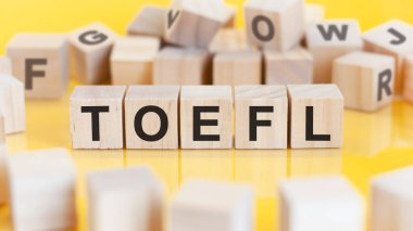 Toefl kelimesi tahta küp yapısına yazılmıştır. Parlak bir arkaplanda engeller. finansal konsept. Seçici odaklanma. toefl - yabancı dil olarak İngilizce sınavının kısaltılmışı