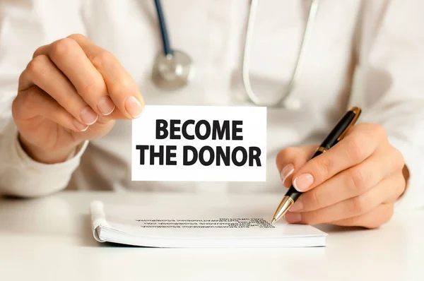 Doctors hands a sheet of paper with text BECOME THE DONOR, medical concept — Stock Photo, Image