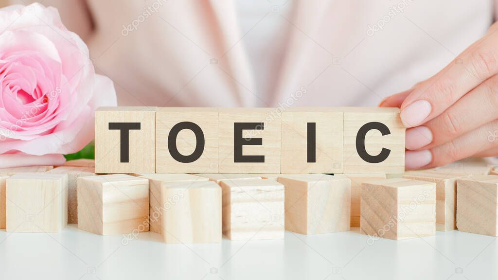 toeic text on wooden block in hand, concept