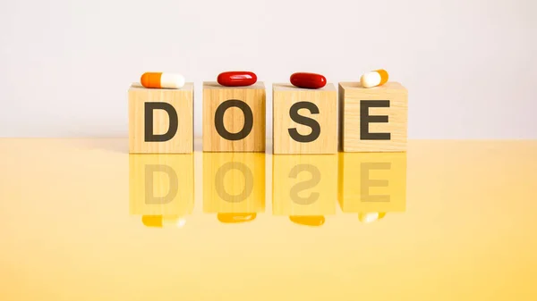 Word Dose Made Wooden Cubes Yellow Background Pills Medical Concept — Zdjęcie stockowe