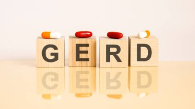Gerd kelimesi sarı arkaplandaki tahta küplerden ve haplardan oluşur. tıbbi tedavi, önleme ve yan etkiler kavramı