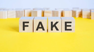 Tahta bloklardaki sahte kelime sarı masada yatıyor. Etrafında harfler olan iş konsepti oyuncak blokları. seçici odak