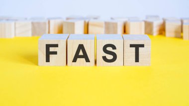 Sarı masada yatan tahta bloklar hakkında hızlı bir söz. Etrafında harfler olan iş konsepti oyuncak blokları. seçici odak