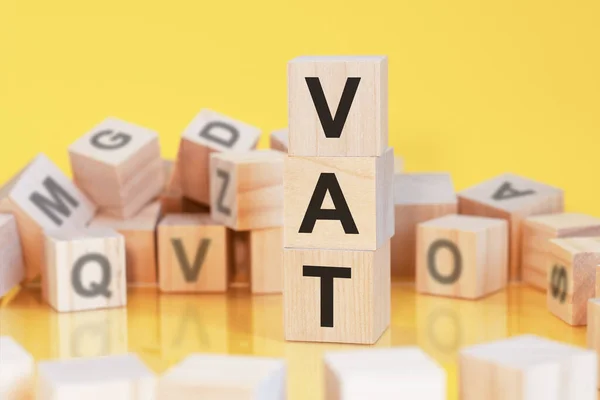 Wooden Cubes Letters Vat Arranged Vertical Pyramid Yellow Background Reflection — Stock Photo, Image