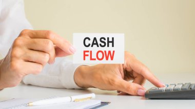 nakit akışı, iş yerindeki hesap makinesinin tuşuna basan kadın tarafından gösterilen kartvizitteki mesaj, seçici odak, iş ve mali konsept